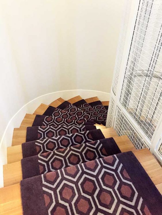 tapis violet géométrique dans un escalier en bois