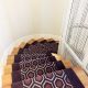 tapis violet géométrique dans un escalier en bois