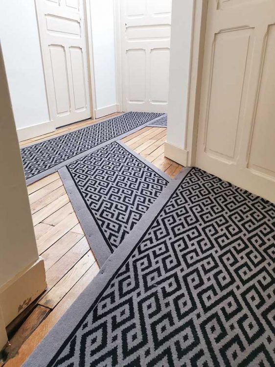 tapis noir et gris géométrique dans un couloir d'immeuble