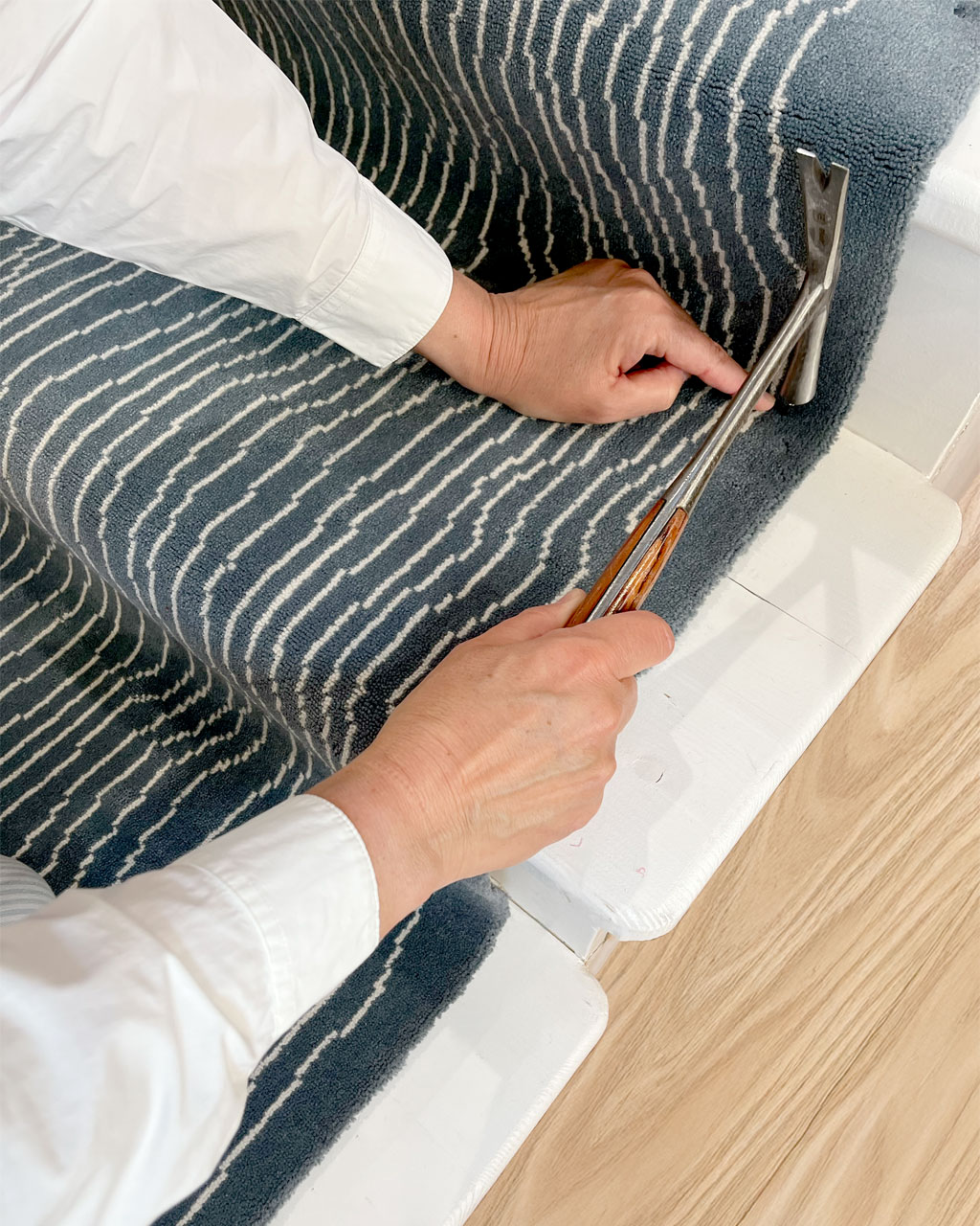 Pose clouée d’un tapis d’escalier par un artisan