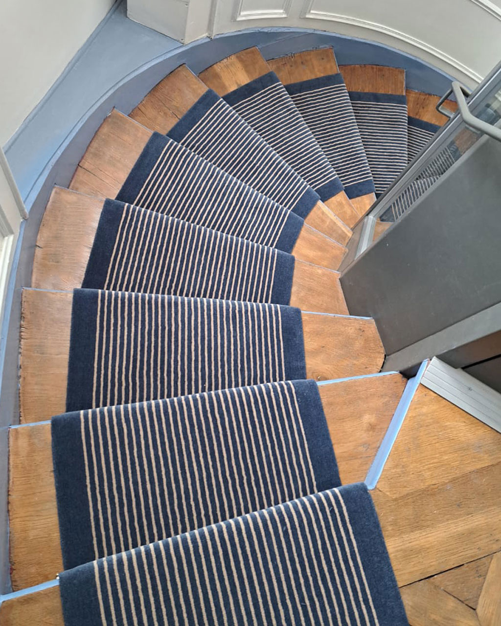Tapis Escalier modèle tout rayé posé dans un escalier tournant en bois